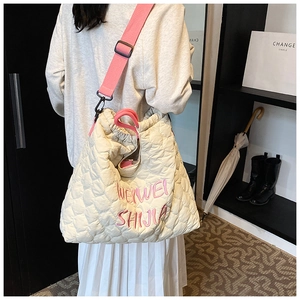 Detail of heart-quilted puffer tote with pink straps and embroidered branding