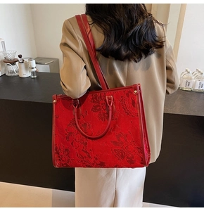 Detail of red floral jacquard tote bag featuring gold rivets and versatile shoulder strap