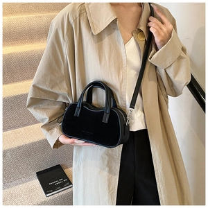 Detail of black velvet Boston bag with leather trim and detachable shoulder strap on model