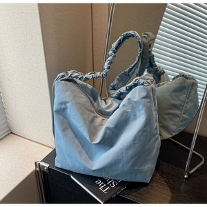 Close-up of light blue pleated shoulder bag with ruffles and mirror reflection details