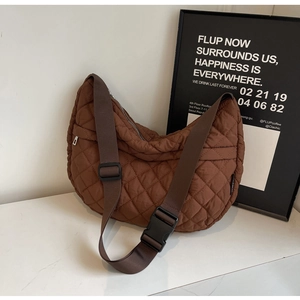 Détail d'un sac demi-lune marron matelassé avec bandoulière réglable et boucle en résine