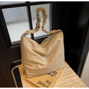 Close-up of beige nylon shoulder bag with ruffled strap detail and hobo design