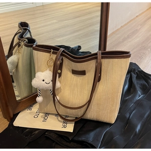 Détail du cabas texturé beige avec anses en cuir marron et breloque nuage en peluche