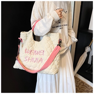 Quilted tote bag detail showing embroidery and adjustable pink canvas shoulder strap