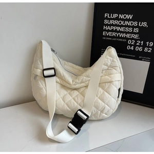 Détail du sac matelassé crème avec bandoulière large réglable et fermeture à boucle