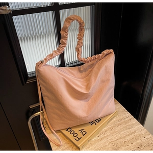 Detail of pink nylon shoulder bag showing delicate pleated texture and elastic strap design