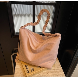 Detail of the light pink tote bag with unique scrunchie strap on marble surface
