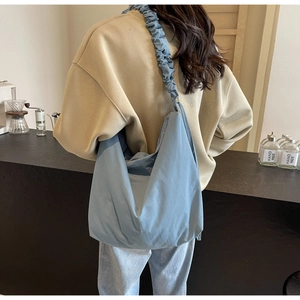 Detail of light blue pleated strap tote bag made of lightweight nylon in cafe setting