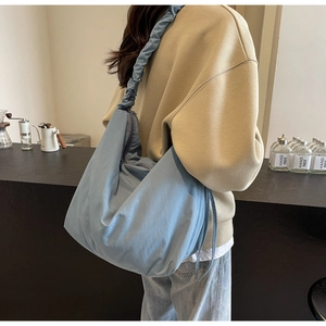 Detail of light blue pleated strap tote bag on model in a cozy cafe setting