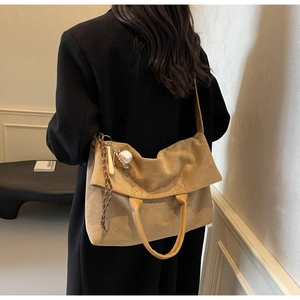 Dettaglio della borsa tote in pelle scamosciata kaki con ciondolo mini baseball