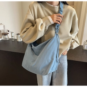 Detail of light blue crossbody bag with pleated shoulder strap and nylon fabric texture
