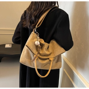 Dettaglio macro della borsa tote in pelle scamosciata kaki con ciondolo da baseball