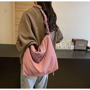 Detail of a purple large capacity shoulder bag featuring a unique ruched wide strap design