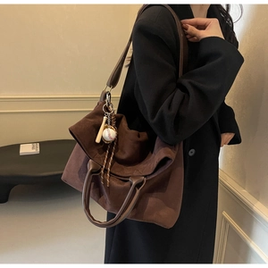 Dettaglio della borsa tote in pelle scamosciata marrone con ciondolo da baseball