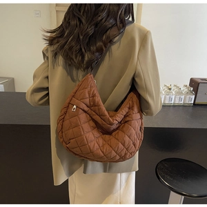 Détail du sac bandoulière matelassé marron en forme de lune porté par un mannequin
