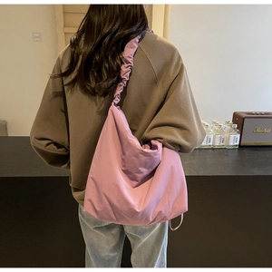 Detail of a lavender slouchy shoulder bag with wide ruched cloud straps in a cozy setting