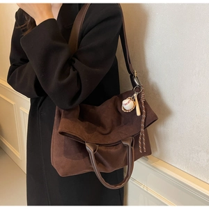 Vista laterale di una grande borsa tote marrone scamosciata indossata sopra un cappotto nero