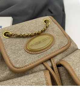 Détail du rabat du sac à dos en toile avec bordure en cuir brun et chaîne dorée