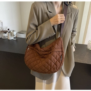 Détail d'un sac lune matelassé marron avec texture en nylon et large bandoulière en tissu