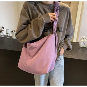 Detail of purple crossbody bag featuring lightweight ruched wide shoulder strap design