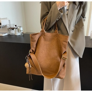 Dettaglio della borsa tote in pelle scamosciata marrone con nappa intrecciata e tracolla