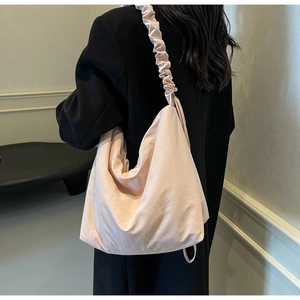 Model wearing a large light pink nylon tote bag with unique ruched shoulder strap detail