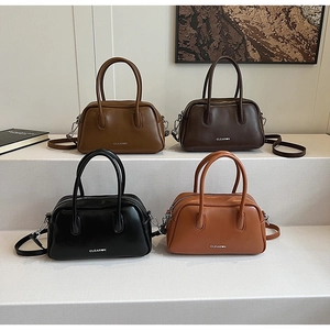 Detalle de bolsos Boston vintage en marrón, caramelo y negro con acabado de cuero sintético