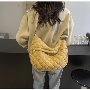 Gros plan sur le sac croissant matelassé jaune gingembre avec bandoulière large et zip argenté