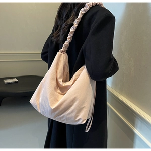 Detail view of the light pink hobo bag featuring a decorative ruffled shoulder strap design