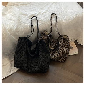 Detail of leopard print tote bags in brown and grey colors on a textured bed sheet