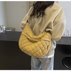 Détail d'un sac jaune gingembre matelassé avec bandoulière réglable en situation réelle