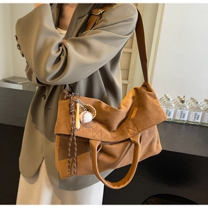 Dettaglio della borsa in pelle scamosciata marrone con ciondoli baseball vintage