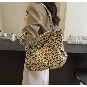 Détail d'un grand sac cabas à imprimé léopard porté avec un blazer dans un café moderne