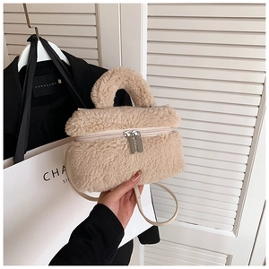 Detailopname van beige faux fur bucket bag met dubbele metalen ritsen en pluche materiaaltextuur