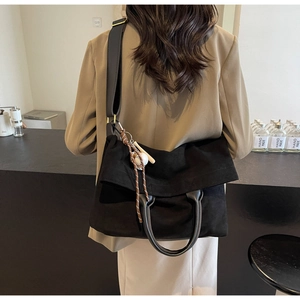 Dettaglio di una borsa nera pieghevole con ciondolo da baseball indossata dal modello