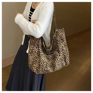 Side view of large leopard print tote bag with long straps worn on shoulder by model