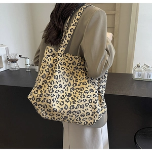 Détail d'un grand sac cabas en toile à imprimé léopard porté par un mannequin en café