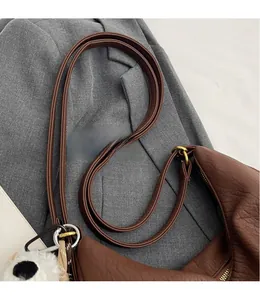 Close-up of brown textured leather strap and gold-tone metal hardware with panda charm