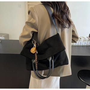 Dettaglio di borsa tote vintage nera con manico in pelle e ciondolo a forma di animale