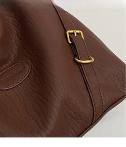 Detail view of dark brown pebbled leather bag with gold hardware and fashion logo
