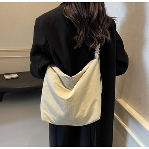 Detail shot of the creamy canvas shoulder bag featuring pleated strap and soft drape design