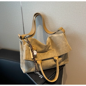 Dettaglio borsa tote in pelle scamosciata kaki con ciondolo da baseball su panca