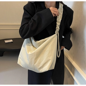 Detail of soft cream white crossbody bag with ruched drawstring shoulder strap on black coat