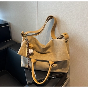 Dettaglio borsa shopper in camoscio marrone con ciondolo da baseball e tracolla in pelle