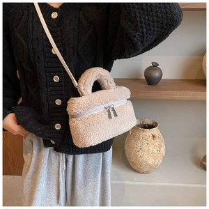 Detail van beige pluche crossbodytas met zilveren dubbele ritsen en leren schouderriem
