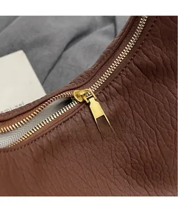 Macro shot of brown pebble grain leather bag with premium gold metal zipper hardware