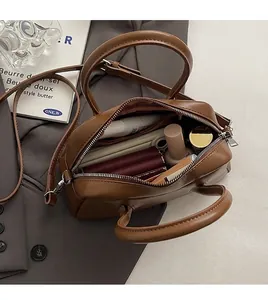 Vista interior que muestra la gran capacidad y compartimentos del bolso de cuero marrón
