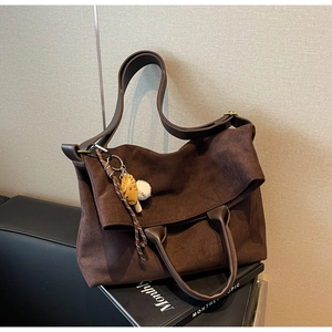 Dettaglio della borsa tote in pelle scamosciata marrone scuro con ciondoli e tracolla