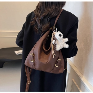 Brown litchi grain hobo bag with adjustable strap and plush bear charm shown on model