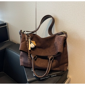 Dettaglio della borsa tote in pelle scamosciata marrone scuro con ciondolo da baseball